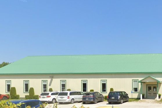 Crossroads Victory Church, a long low building with a green metal roof and a gabled entrance, cars parked along the front