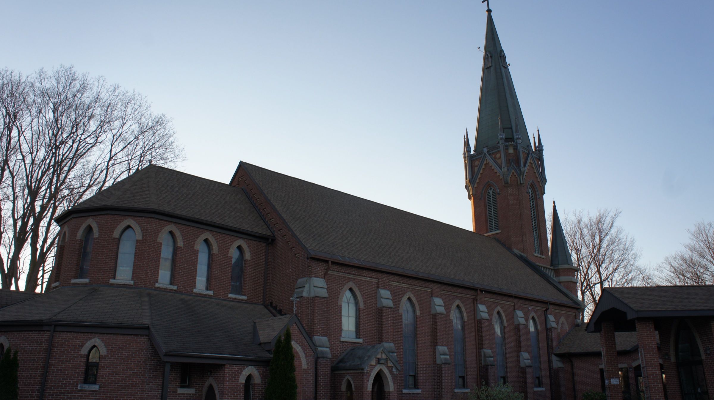 St. Mary of the Assumption, a stone church with a tall spire above its corner entrance tower, seen from the street
